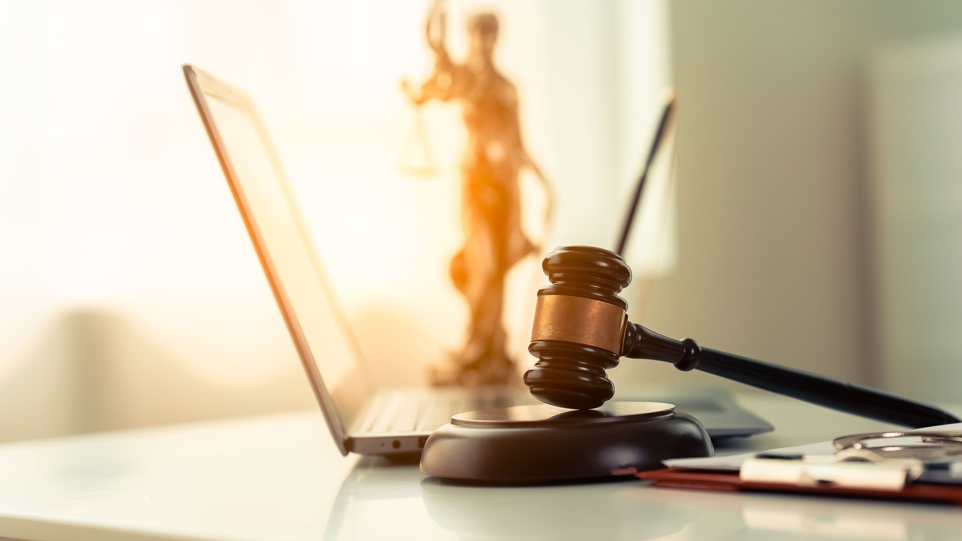 Online law and justice concept on table in modern office Next to the wooden hammer and scales of justice on the table, a close-up figure